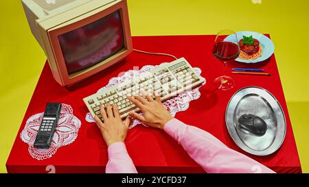 Close-up of hand using computer mouse placed on silver platter, with spaghetti resting on keyboard. Image mixes work and food in strange way. Stock Photo