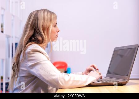 Focused woman working on laptop in modern office space Stock Photo