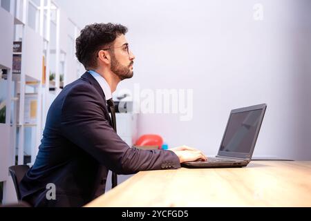 Focused man working on laptop in modern office space Stock Photo