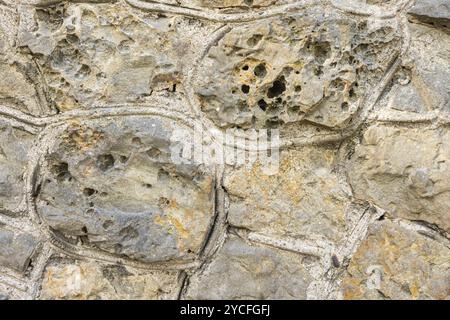 Natural stone wall made of granite stones and white mortar, background image Stock Photo