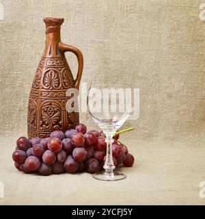 Still-life - clay bottle, grapes and a glass on canvas Stock Photo