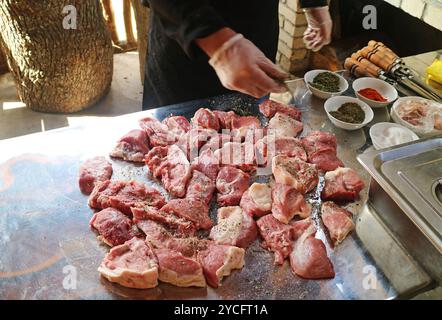 Chef Sprinkling Herbs and Spices on Raw Pork for Cooking Traditional Armenian Barbecue or Khorovats Stock Photo