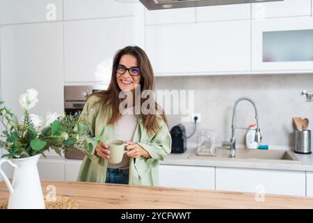 Life goals, simple living and morning routine. Young beautiful woman living alone, daydreaming in her new apartment, moved in after job promotion and Stock Photo