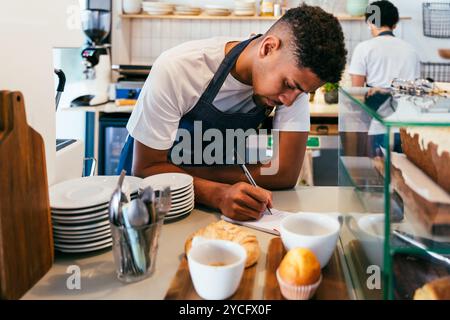 Bakery, happy portrait of hispanic black man and woman in cafe ready for serving pastry, coffee and baked foods - Confident waiter barista by counter Stock Photo