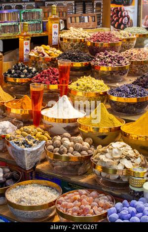 Golden bowls filled with assorted dried flowers and herbs are displayed at a spice market in Dubai City, UAE. Stock Photo