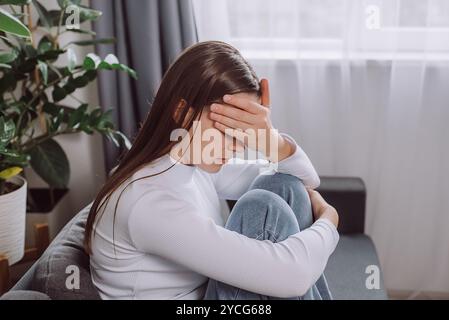 Depressed unhappy young brunette woman expression face thinking about problem sitting on couch, difficulty, feeling failure and exhausted, suffering f Stock Photo