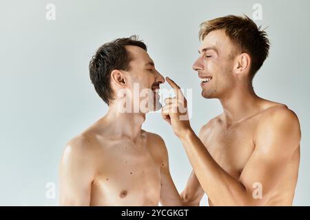 Two young men share a delightful moment, embracing love and connection with joyful smiles. Stock Photo