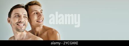 Two young men share a moment of happiness, smiling against a light backdrop. Stock Photo