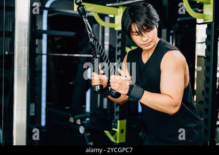 Young man performing cable triceps pulldowns to build muscle and strength Stock Photo