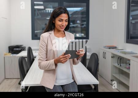 Indian businesswoman in a company office, working on a tablet. Business and managers concepts. Stock Photo