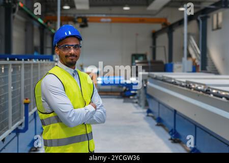 Production line engineer in a factory with yellow vest and blue helmet at work. Stock Photo