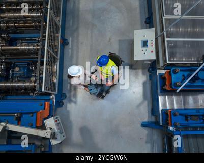Worker with disability consulting with a woman manager in the factory, analyzing graphs and data on a tablet to improve production processes, top down Stock Photo