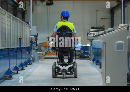Production line engineer with disability in a factory with yellow vest and blue helmet at work. Stock Photo