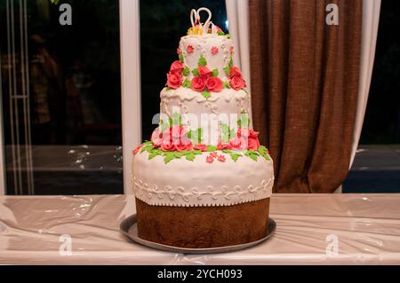 Elegant Three-Tier Wedding Cake Adorned with Pink Roses and Green Leaves. Stock Photo