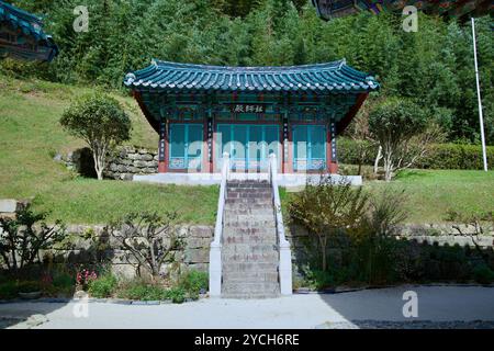 Ulsan, South Korea - October 21st, 2023: A small, intricately decorated pavilion with vibrant teal doors at Seoknamsa Temple, set against a backdrop o Stock Photo