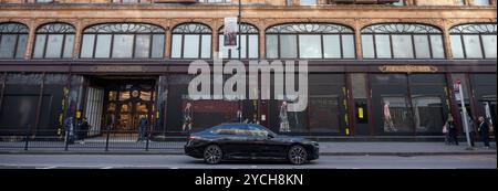 Harrods Knightsbridge, London, UK. 23rd Oct, 2024. The frontage of Harrods displays a digital presentation of models walkings across the ground floor windows, promoting Italian fashion brand Moncler Genius, The City of Genius. Credit: Malcolm Park/Alamy Live News Stock Photo