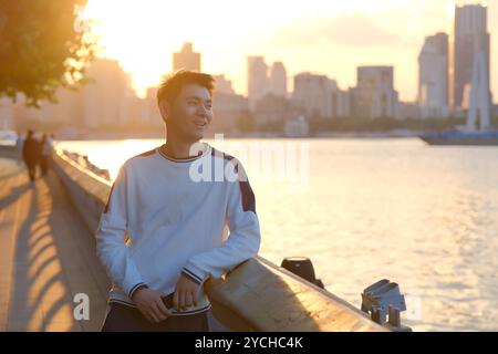 smiling handsome Asian young man in sunset dusk sunlight outdoor Stock Photo