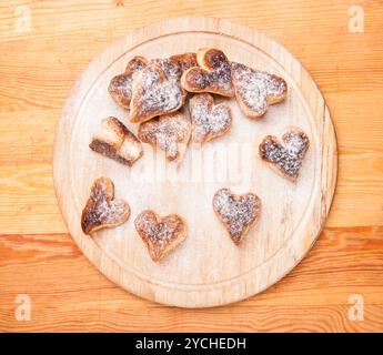 Bakery hearts from split pastry with sugar powder on wooden Stock Photo