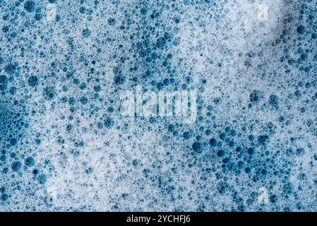 Background and pattern. White soap foam with bubbles, texture on blue tile background. Detergent foam bubble on tile. shower gel, hair shampoo foam sm Stock Photo