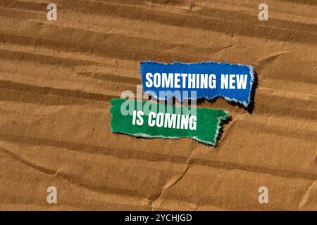 Something new is coming message written on ripped torn paper pieces with cardboard background. Conceptual something new is coming symbol. Copy space. Stock Photo