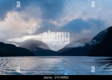 A clearing storm at sunset creates misty clouds over the calm waters of K'ootz Inlet in the Great Bear Rainforest of British Columbia, Canada Stock Photo
