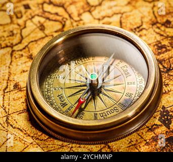 Vintage compass lies on an ancient world map. Stock Photo