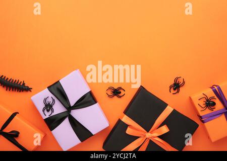 Happy Halloween holiday concept. Flat lay gift boxes, orange pumpkins, bats, spiders on orange background. Halloween greeting card template. Top view Stock Photo