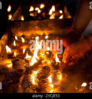 People burning oil lamps as religious ritual in Hindu temple. India Stock Photo