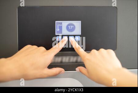 Adjusting temperature settings on a modern appliance display in a kitchen Stock Photo