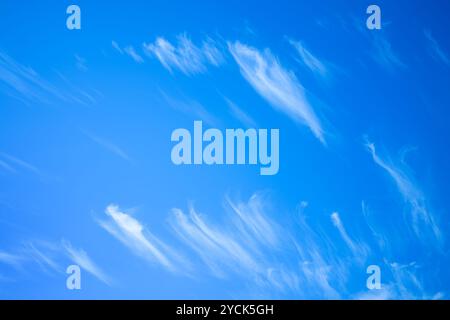 blue sky with light, wispy clouds scattered across it. Stock Photo