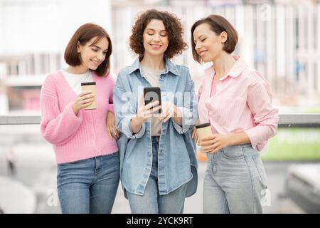Three friends enjoying coffee while sharing laughs and checking their phones Stock Photo