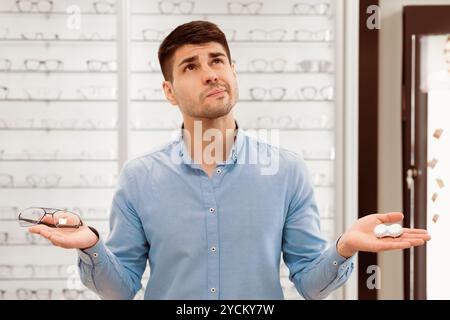 Pensive man choosing between eyeglasses and contacts Stock Photo