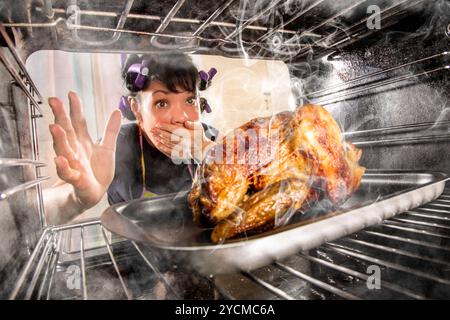 Funny Housewife overlooked roast chicken in the oven, so she had scorched, view from the inside of the oven. Housewife perplexed and angry. Loser is d Stock Photo