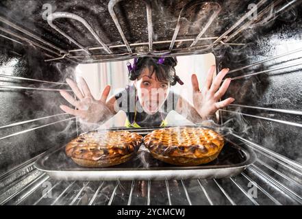 Funny Housewife overlooked cakes in the oven, so she had scorched, view from the inside of the oven. Housewife perplexed and angry. Loser is destiny! Stock Photo