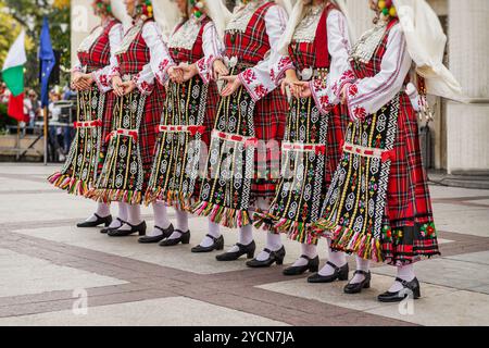 Women dressed in colorful traditional folk costumes dancing in cultural festival Stock Photo