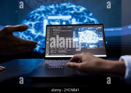 Technician and colleague use AI cognitive computing to extract information from complex data on laptop. Close up of teamworking IT experts using artificial intelligence on notebook Stock Photo