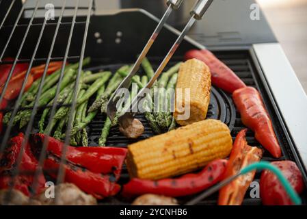 Delicious grilled vegetables asparagus, paprika and corn cob on barbecue grill with smoke and flame. Stock Photo