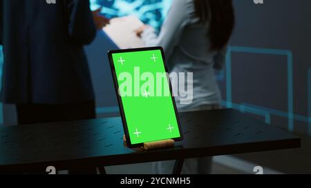 Green screen tablet used by computer scientists in startup doing advancements in AI field. Employees working on mockup device in workspace featuring artificial intelligence systems, camera A Stock Photo
