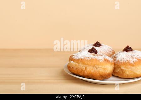 Plate with tasty donuts for Hanukkah celebration on wooden table against color background Stock Photo