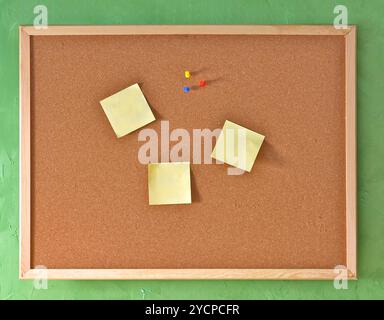 Horizontal cork board with yellow blank notes and pins Stock Photo