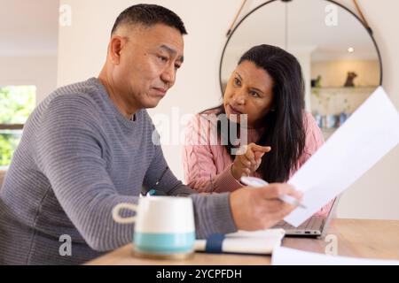 Multiracial senior couple discussing finances at home, reviewing documents together seriously Stock Photo