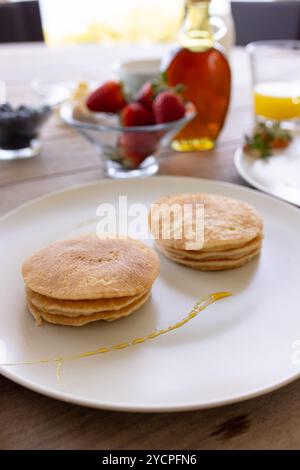 Pancakes with syrup and fresh fruit on breakfast table, ready to enjoy, at home Stock Photo