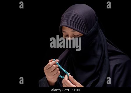 Portrait Asian Muslim woman wearing black hijab is praying for prayer with faith and determination. on black background. Stock Photo