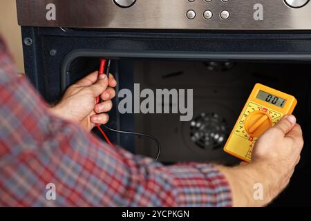 Repairman testing oven element with multimeter, closeup Stock Photo