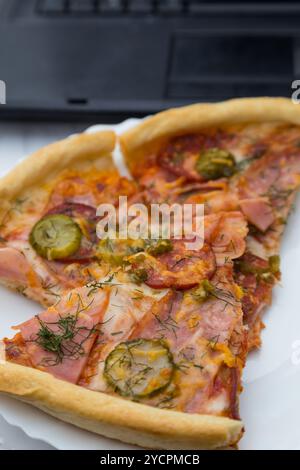 Pieces pizza on laptop keyboard background Stock Photo