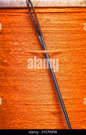 Spool of yellow thread with a needle stuck in it. Stock Photo