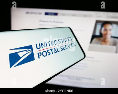 In this photo illustration, a cellphone with the logo of American agency United States Postal Service (USPS) is seen in front of website. Stock Photo