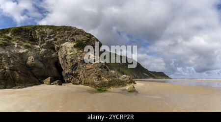 A panorama landscape view of Maghera Beach with the entrance to one of the caves in the rocks Stock Photo