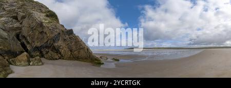 A panorama landscape view of Maghera Beach with the entrance to one of the caves in the rocks Stock Photo