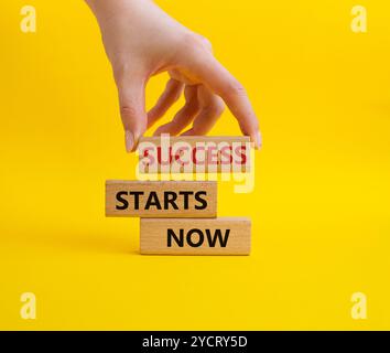 Success Starts Now symbol. Concept words Success Starts Now on wooden blocks. Businessman hand. Beautiful yellow background. Psychological social and Stock Photo